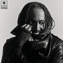Thundercat pictured in black and white wearing a dark leather jacket, biting the collar.